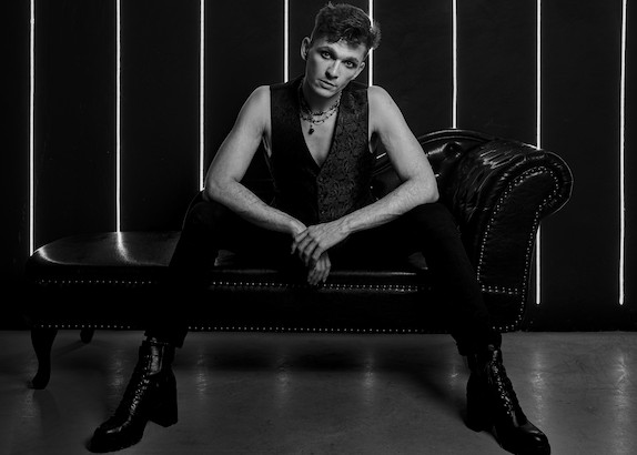 Męska fotografia wizerunkowa - mężczyzna na szezlongu w mrocznym, stylowym oświetleniu studyjnym.