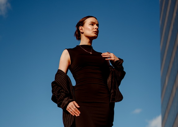 Fotografia wizerunkowa i fashion - Justyna w czarnej stylizacji na tle błękitnego nieba i architektury Gdyni.